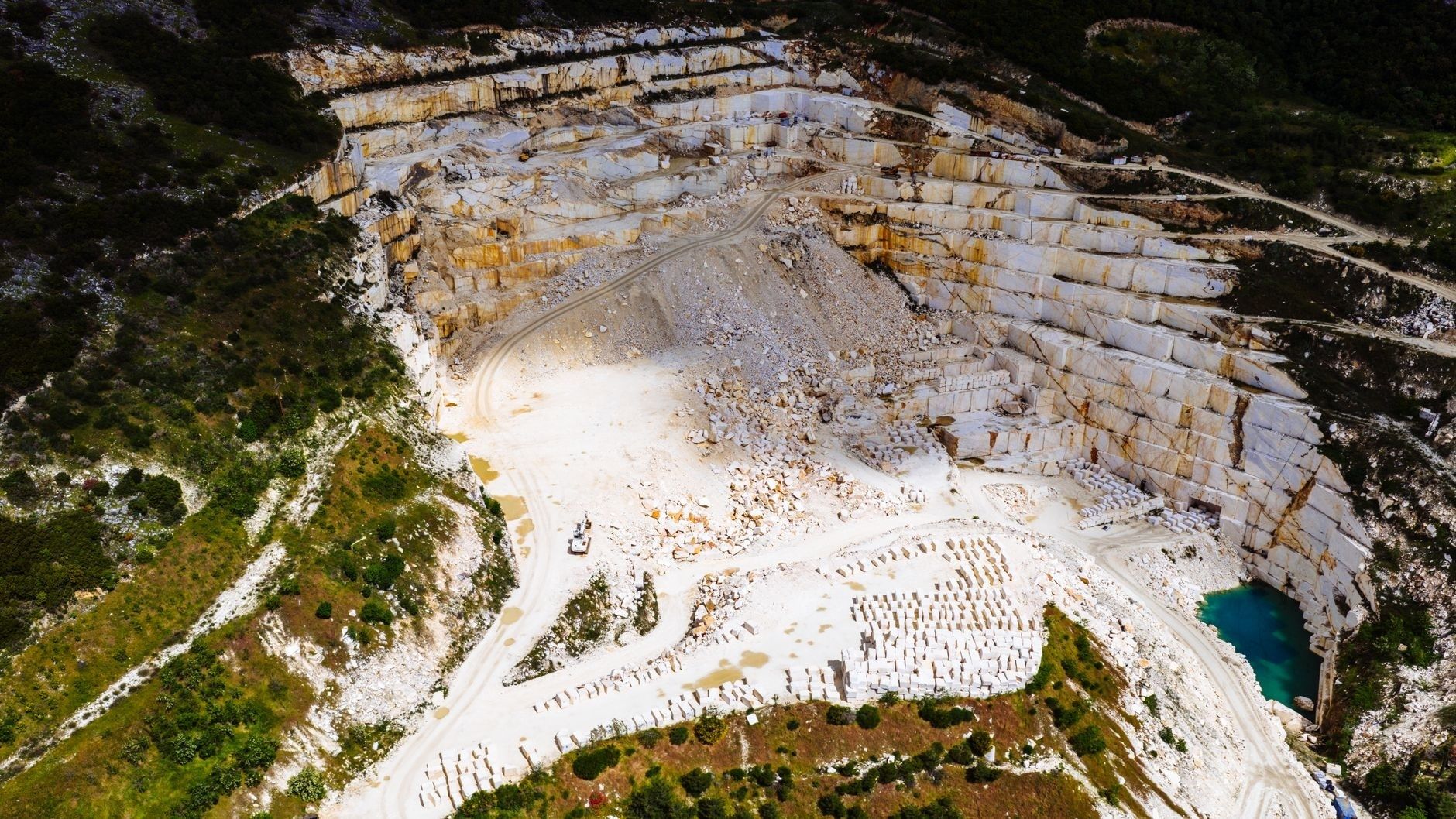 Luchtfoto van een grote kalksteengroeve met terrassen en steenblokken