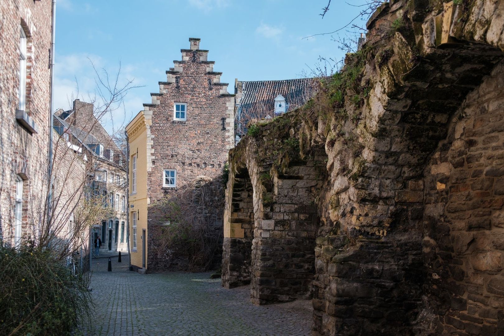 Kasseienstraat met historische bakstenen gevels en een oude stadsmuur
