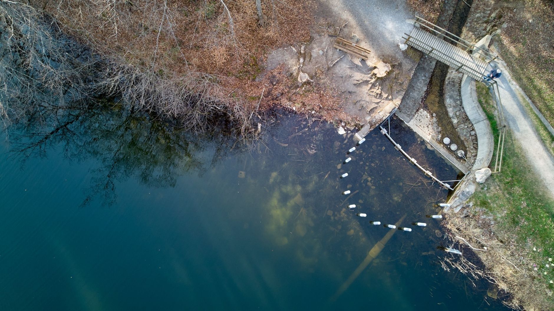 Luchtfoto van een waterplas met brug en oeversporen